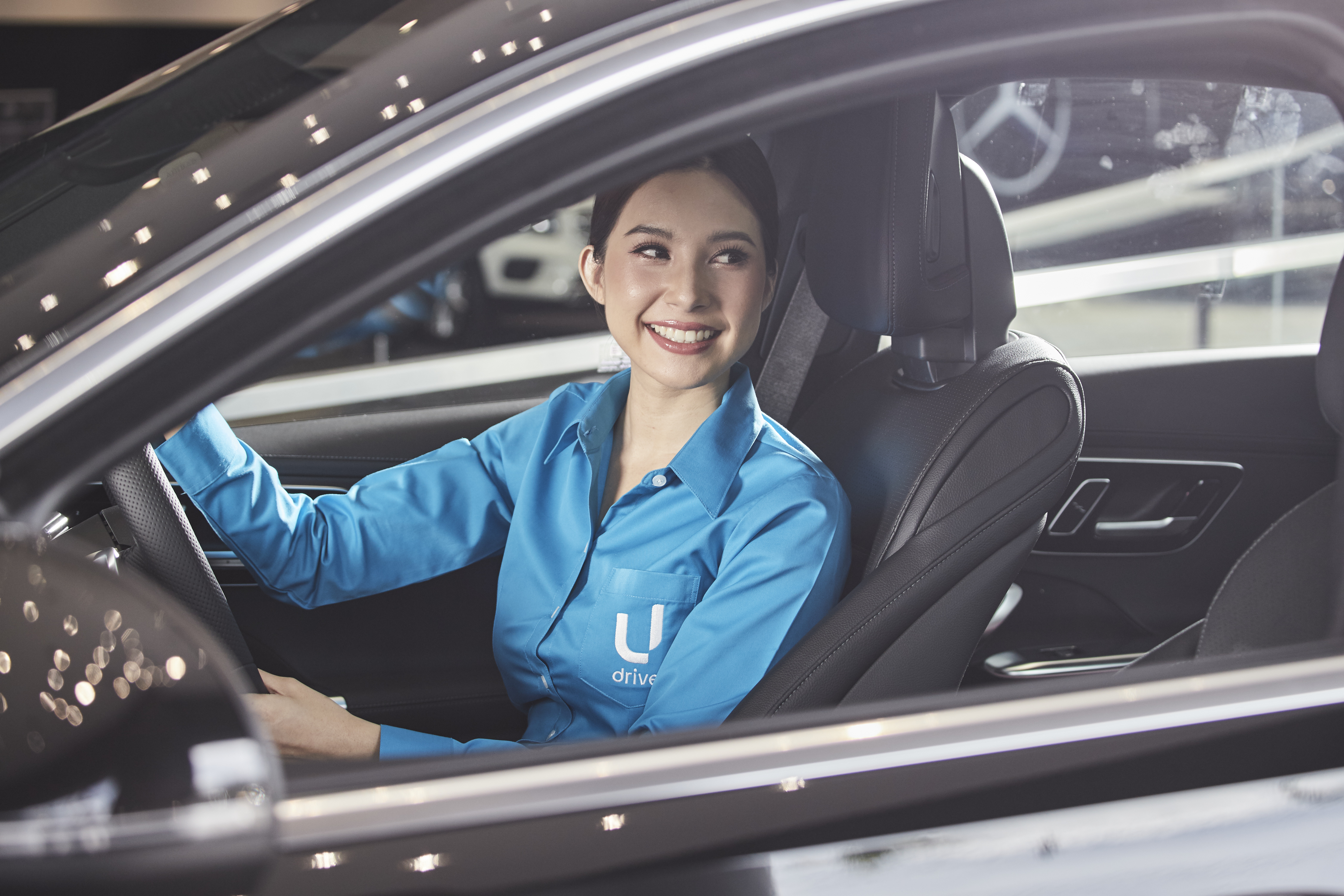 พนักงานขับรถหญิง U Drink I Drive ในชุดยูนิฟอร์มสีฟ้า นั่งประจำที่คนขับ